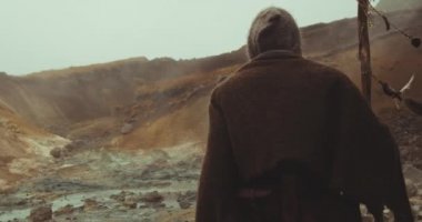 Kapüşonlu Adam Çölde bir manzara gibi yürüyor.