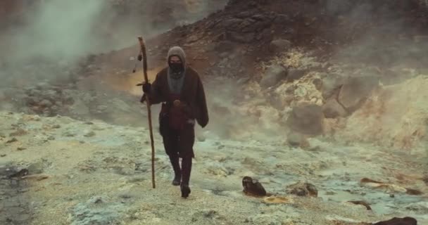 Zakapturzony i zamaskowany człowiek spacerujący po mglistym krajobrazie — Wideo stockowe