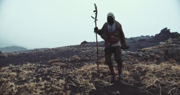 Hombre encapuchado caminando sobre arena negra — Vídeo de stock