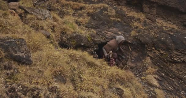 Hombre encapuchado y enmascarado saliendo de la cueva Hillside — Vídeo de stock