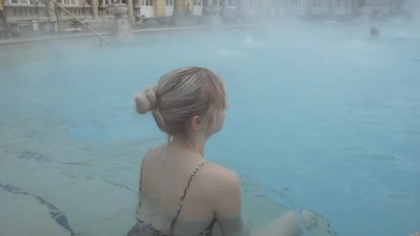 Vrouw zit bij rand van het zwembad met warme stoom afkomstig van Blue Pool Waters — Stockvideo