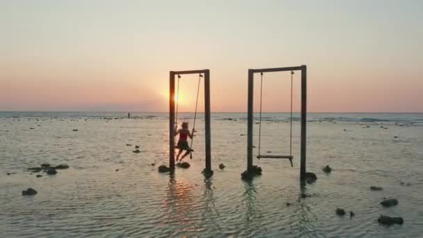 Femme balançant sur le siège au coucher du soleil — Video