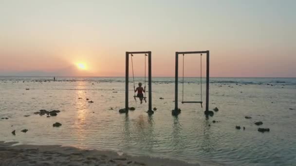 Woman On Rope Swing In Sea At Sunset — Stock Video