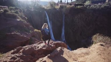 Ouzoud Falls 'un yanındaki uçurumun kenarında duran bir turist.