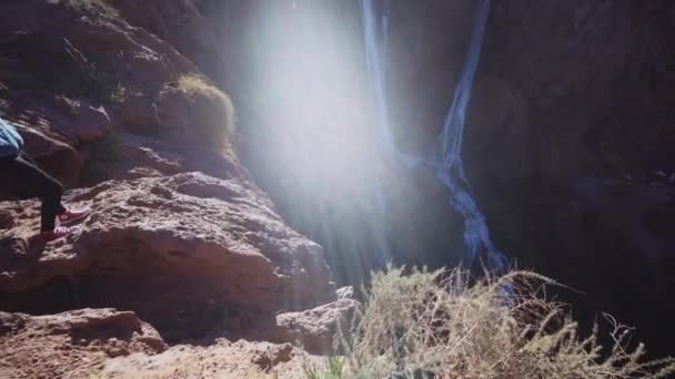 Женщина, стоящая на краю скалы рядом с водопадом Узуд — стоковое видео