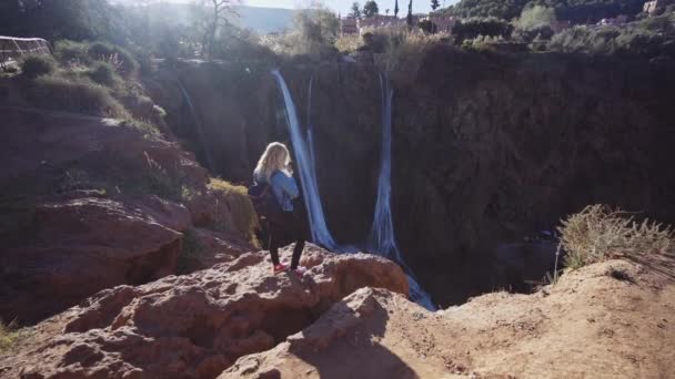 Турист стоїть на краю скелі поруч з водоспадом Узуд — стокове відео