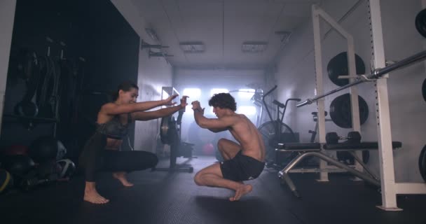 Man och kvinna stretching från knäböj i gym — Stockvideo