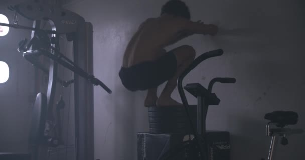 Молодой человек, выступающий в коробке прыгает в спортзале — стоковое видео