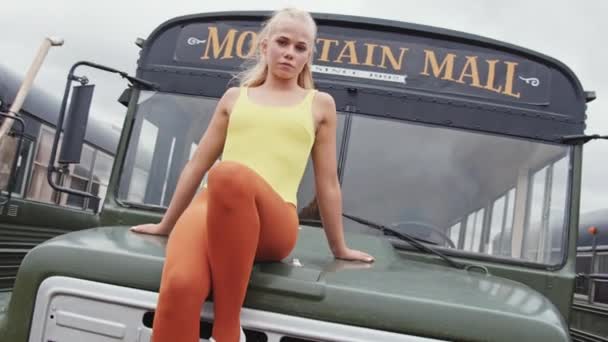Cool dansare i gul trikå på huva av buss — Stockvideo