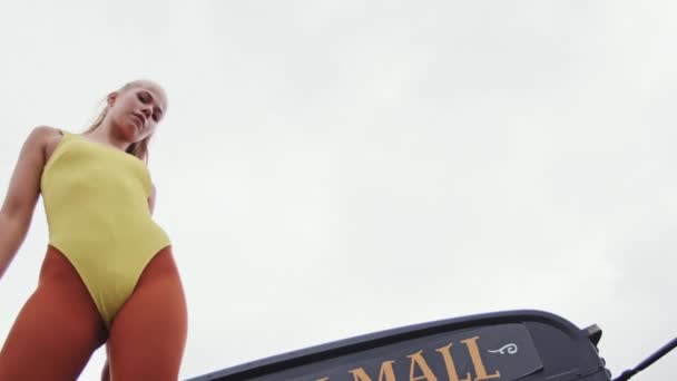 Young Woman In Yellow Leotard On Bus Hood — Stock Video