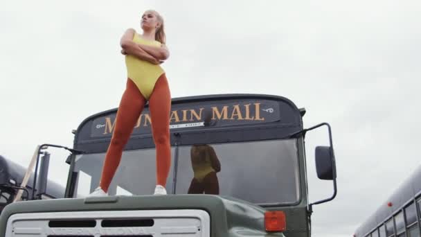 Coole Frau in Gelb, die auf der Bushaube steht — Stockvideo