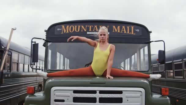 Mulher flexível em amarelo fazendo dividas na capa do ônibus — Vídeo de Stock