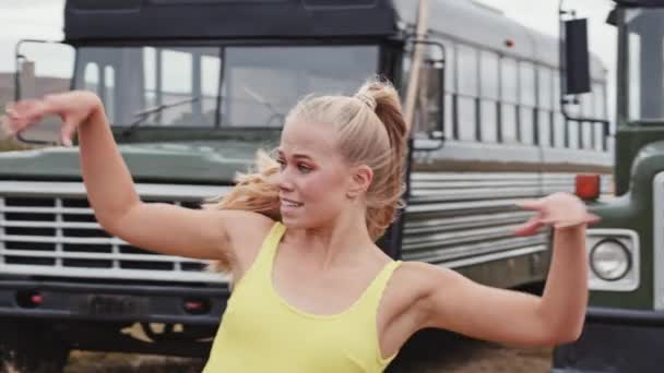 Dansen vrouw in geel in de voorkant van bussen — Stockvideo