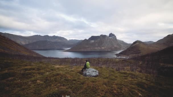 Wanderer auf Felsen sitzend mit Blick auf Fjord und Berge — Stockvideo