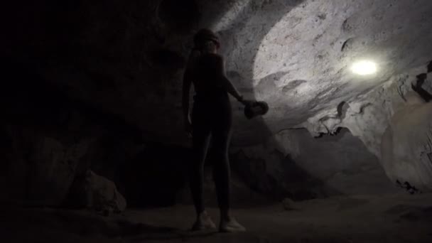 Turista femenina explorando cueva con linterna — Vídeo de stock