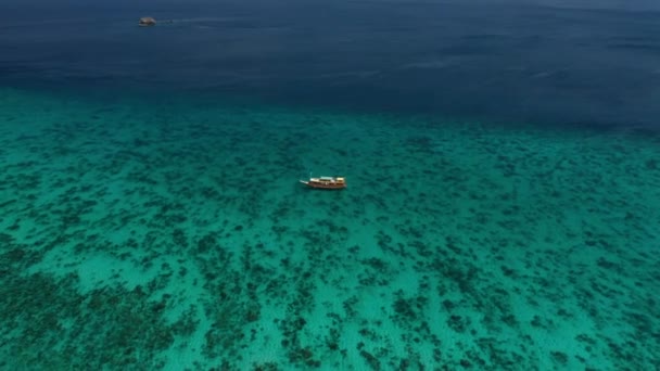 Drone over turquoise zee met aangemeerde boot — Stockvideo