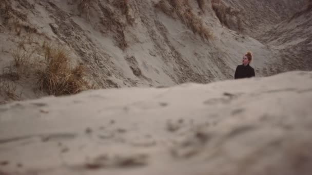 Chica en negro caminando por dunas de arena en la playa — Vídeos de Stock