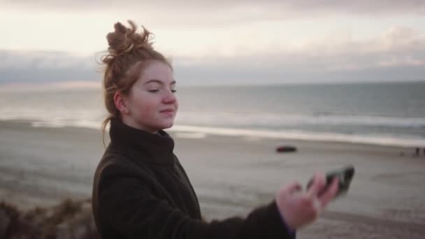 Pelirroja chica tomando selfie en playa — Vídeo de stock