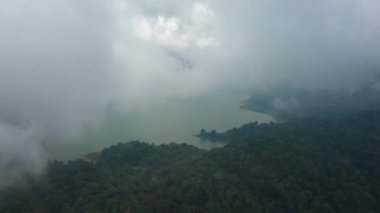 Bulutların arasından araziye ve aşağıdaki göle giden dron