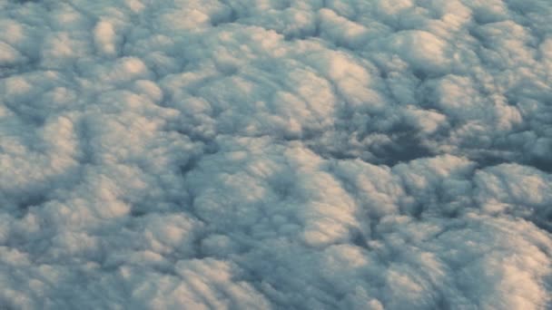 Vuelo del avión sobre nubes iluminadas por el sol que cubren el paisaje — Vídeos de Stock
