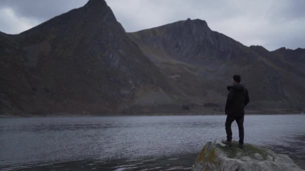 Человек на скалах, смотрящий на фьорд — стоковое видео