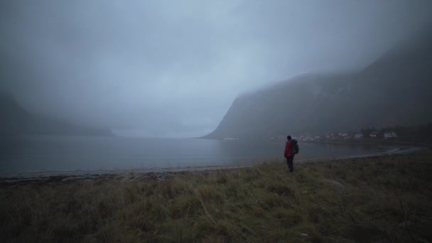 Wandelaar bij Fjord op zoek naar bergen — Stockvideo
