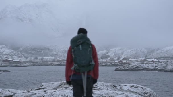 Πεζοπόρος στο χιόνι κοιτάζοντας φιόρδ και βουνά — Αρχείο Βίντεο