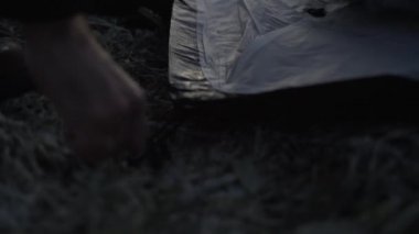 Çadırdan aşağı iten adam Peg 'i Dondurucu Toprağa atıyor.