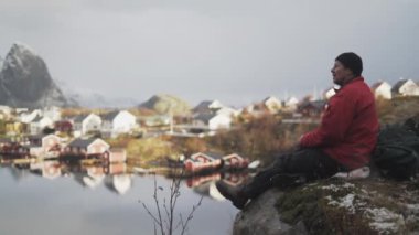 Yürüyüşçü kayalıklarda dinleniyor Reine köyünde