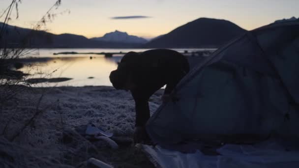 Man sätter upp tält på fryst mark i skymningen — Stockvideo