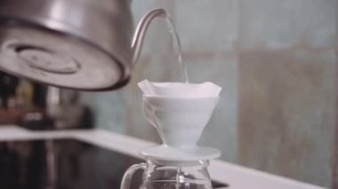 Kahve filtresinden sıcak su dökülüyor.