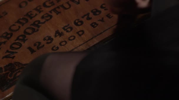 Manos moviendo Planchette sobre Ouija Junta y ortografía Azazel — Vídeo de stock