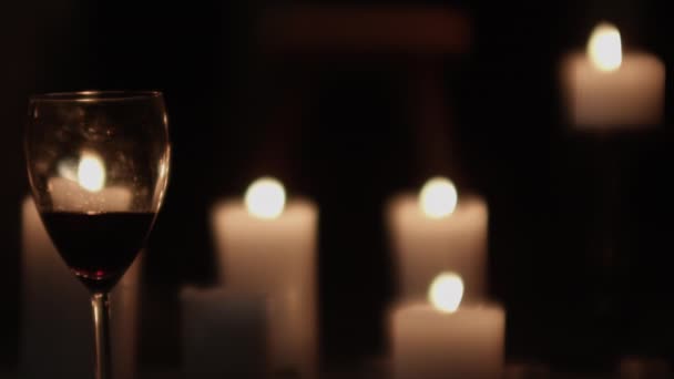 Bicchiere da vino e candele accese soffiate dal vento — Video Stock