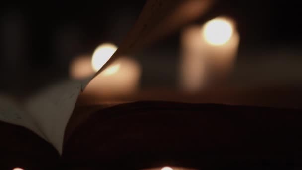 Pages et bougies allumées soufflées par le vent dans la chambre noire — Video