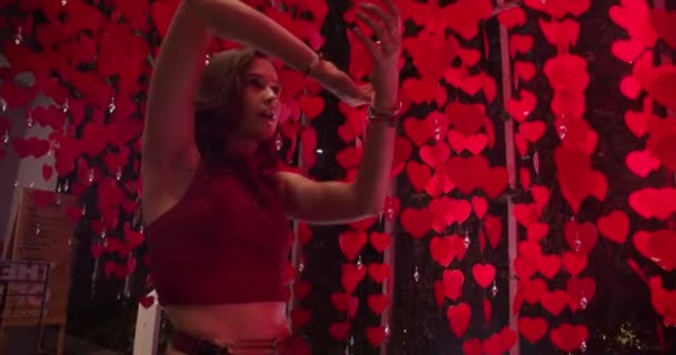Танцювальні кроки жіночої моделі між банерами серця на тлі — стокове відео