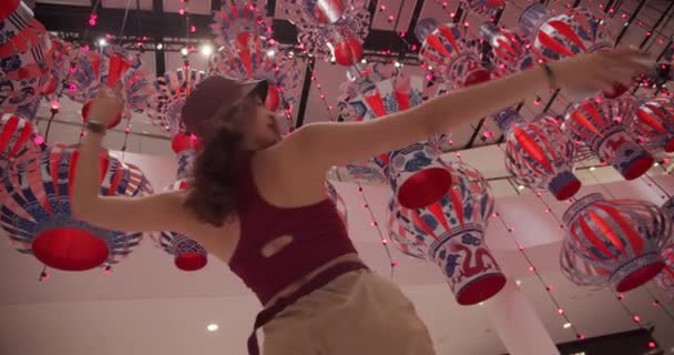 Tiro de mujer de bajo ángulo bailando con linternas de papel colgando en el fondo — Vídeos de Stock