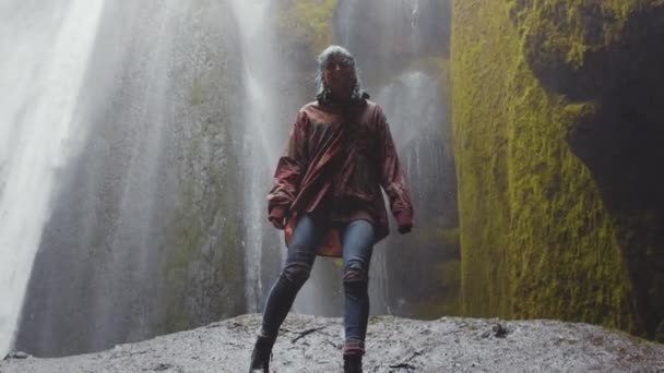 Jovem mulher no rock molhado a partir de cachoeira — Vídeo de Stock
