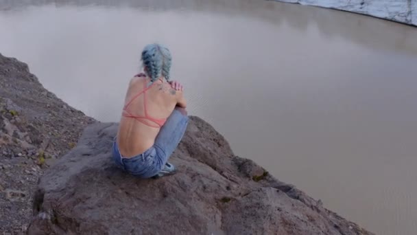 Drone przyczajonej kobiety na skale przez lodowiec — Wideo stockowe