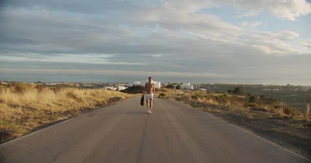 Hombre sin camisa en pantalones cortos caminando camino vacío — Vídeo de stock