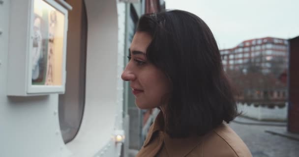 Kvinnan tittar i butiken fönster och leende — Stockvideo