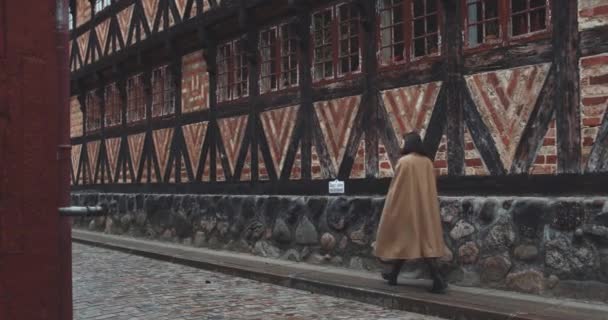 Kvinna i lång rock promenader längs gatan — Stockvideo