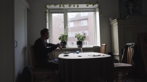 Man dricker kaffe och tittar ut genom fönstret — Stockvideo