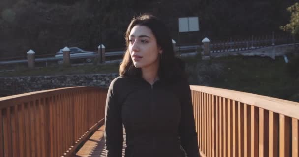 Красива жінка в чорному пальто на мосту — стокове відео