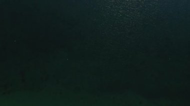 Uçsuz bucaksız deniz suyunun insansız hava aracı vuruşu. Parlak güneş ışınları suları yansıtıyor.