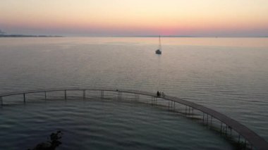 Kızıl Turuncu Gökyüzü ve Sakin Deniz Suyu ile çevrili Sonsuz Köprü