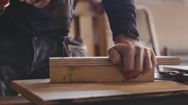 Marangoz delmek için matkap kullanıyor