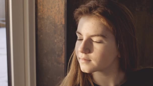 Девочка-подросток, выглядывающая из окна — стоковое видео