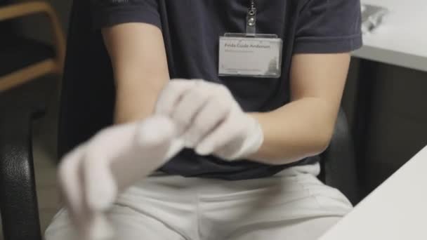 Доктор в маске надевает хирургические перчатки — стоковое видео