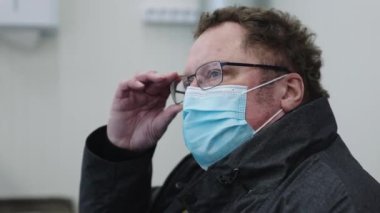 Hastanedeki yüz maskeli ve gözlüklü hasta.