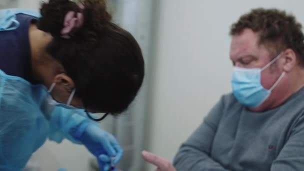 Доктор в скрабах и маске для лица, берущий образец крови — стоковое видео